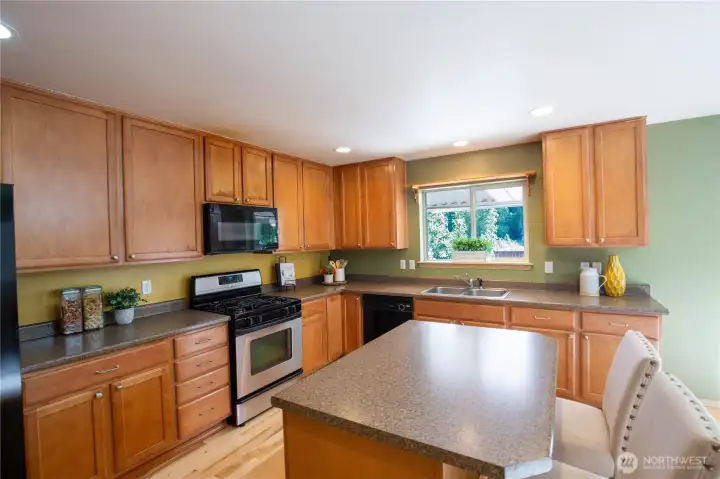 The spacious kitchen has lots of cabinets and work space with more eating and work space at the center island. Room for several chefs at a time for pleasant meal prepping.  Newer refrigerator, microwave, dishwasher, and all appliances stay with the home.