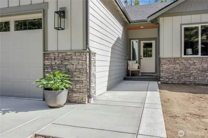 Front door with covered area and front porch looking out to the side yard