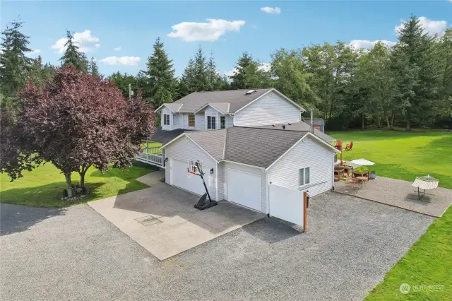 Ample parking, with a 3 car and a manicured gravel drive surrounded by lush green grass.