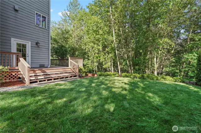 Fully fenced yard surrounded by lush green trees - land behind will not be developed.