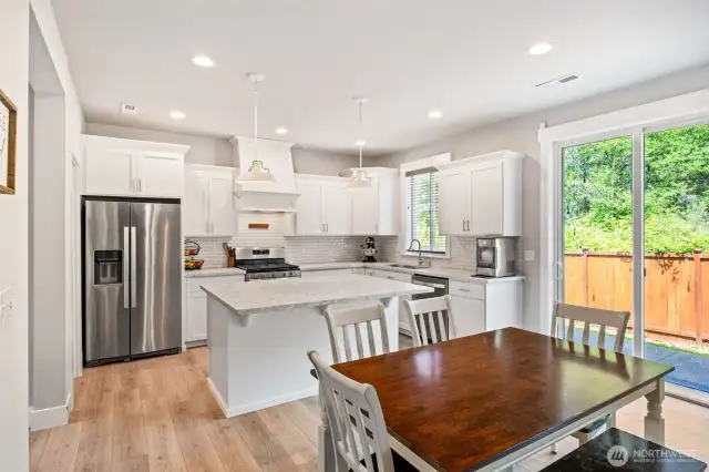 Beautiful open kitchen with quartz counters, tile backsplash, and HUGE walk in pantry.