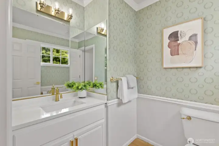 The guest 1/2 bath with quartz vanity, brushed gold faucet and lighting.