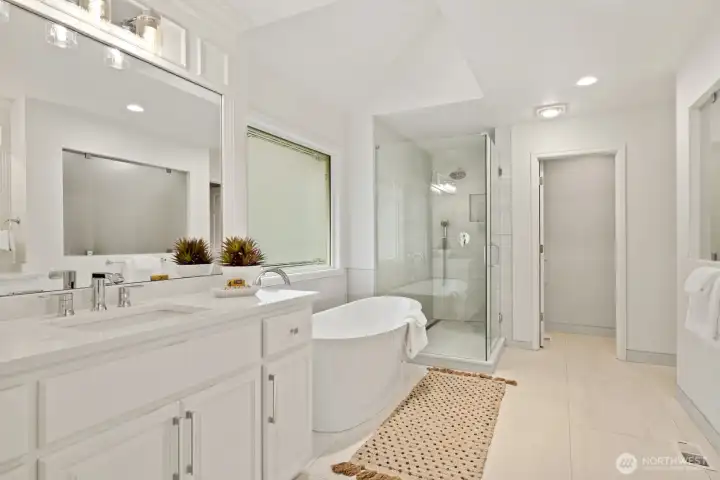 Updated primary bathroom with large format designer tile floor and separate quartz vanities with intricate millwork.