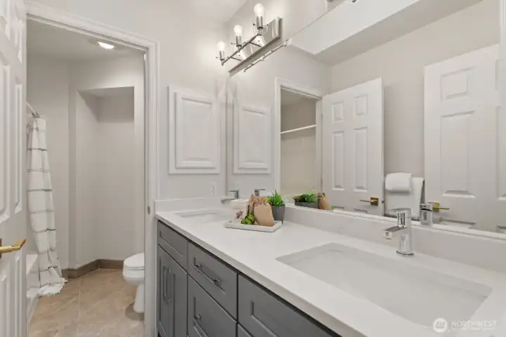 The updated hall bathroom upstairs with new quartz vanity with 2 sinks and tiled floor.