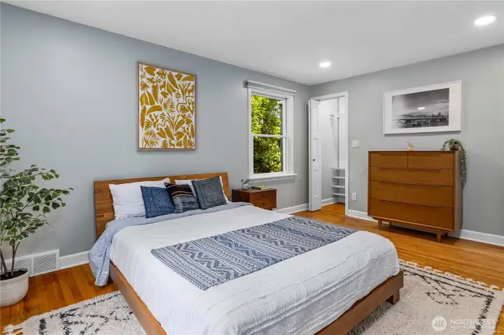 The primary bedroom on the main level features oak floors, lots of natural light, and a closet that is much bigger than it appears.