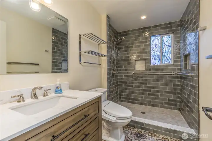 Elegant 3/4 bath on the main level with designer tile flooring and shower surround