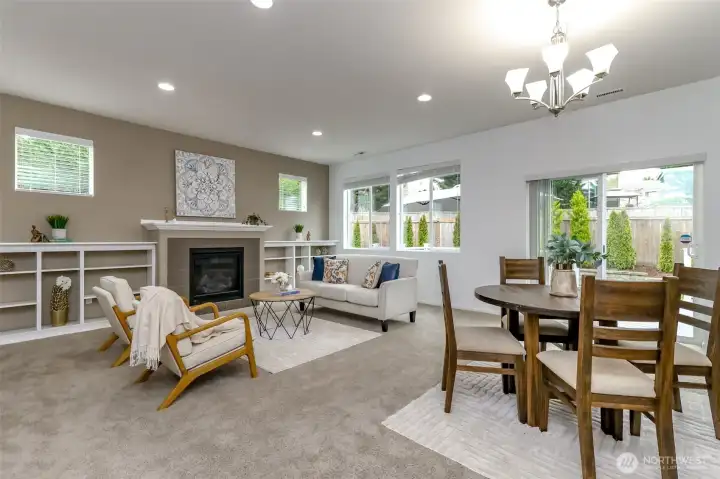 Living room with gas fireplace and built ins. Lots of natural light through these spacious windows and sliding glass doors. The dining room is just off the kitchen island.
