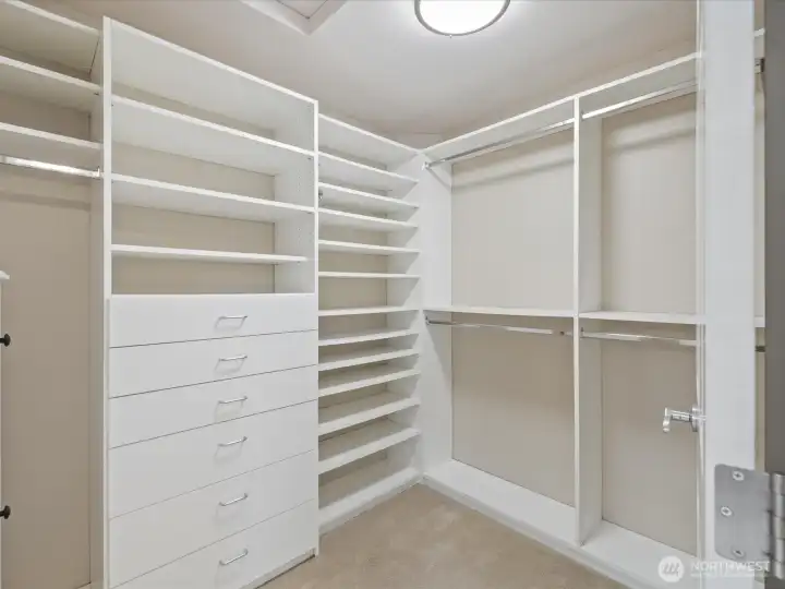 Spacious walk in closet with versatile built in storage.