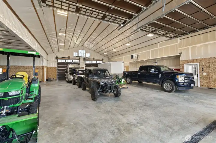 The 4,752 sq ft shop offers abundant space for vehicles, machinery, and recreational toys, featuring six 14’ x 14’ garage doors, including two sets of convenient drive-through access.