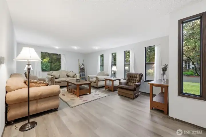 To the right upon entry is this lovely and spacious family room--tons of windows for green views and inviting daylight, new LVP flooring, and fresh paint!