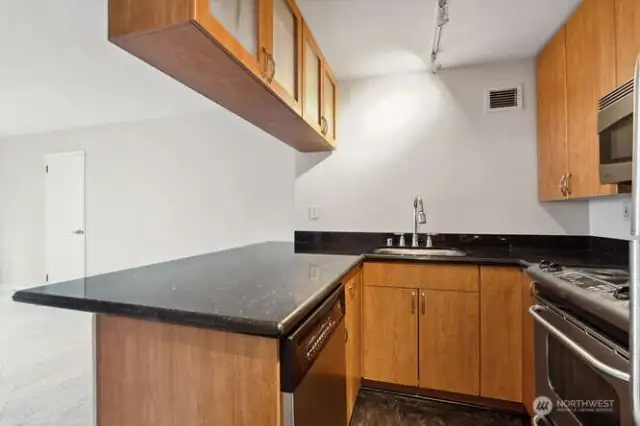 Efficient kitchen with granite counters, cherry cabinets, and stainless appliances.