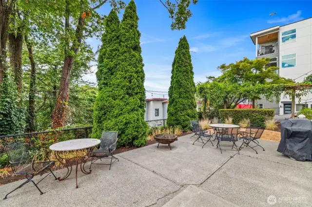 Dappled sunlight filters through mature trees and trellised greenery, while wrought iron seating invites you to linger over morning coffee or evening wine