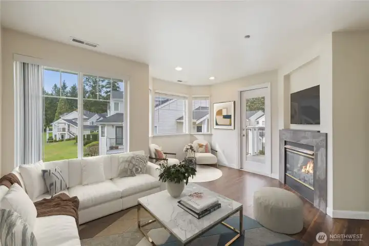 Room off kitchen, often used as a family room. Two-sided gas fireplace on the right. Door leads to deck. Virtually Staged.