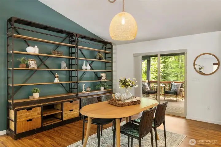 Dining area with vaulted ceilings and covered deck access with stairs to lower yard.