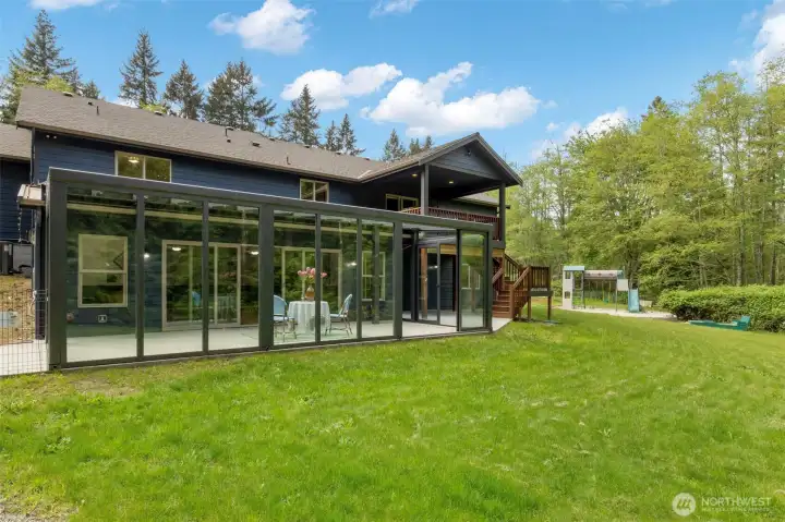 Gorgeous glass room with light built into the ceiling and doors that all slide open. The BEST indoor/outdoor setup! Over 300 sq ft (not included in total square footage). Play set and sandbox off in the distance.