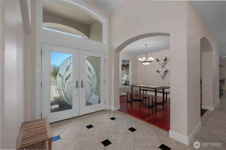 Welcome guests through the arched entry and into a warm dining space with rich wood floors.
