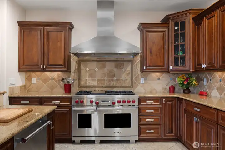 The 40-inch Wolf range, tile backsplash, and warm wood cabinetry highlight the kitchen design.