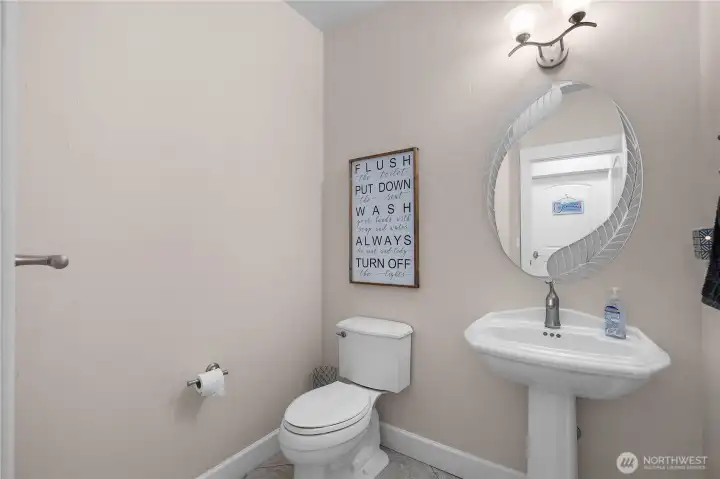 Welcome guests with a clean powder bath featuring pedestal sink and simple finishes.