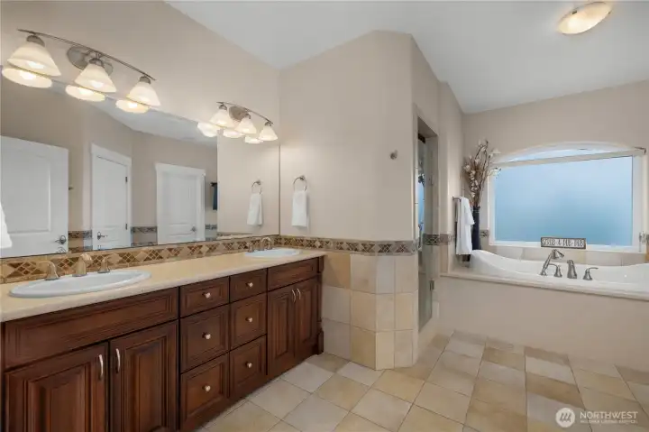 Unwind in the spacious primary bath with dual sinks, deep soaking tub, and tiled shower.