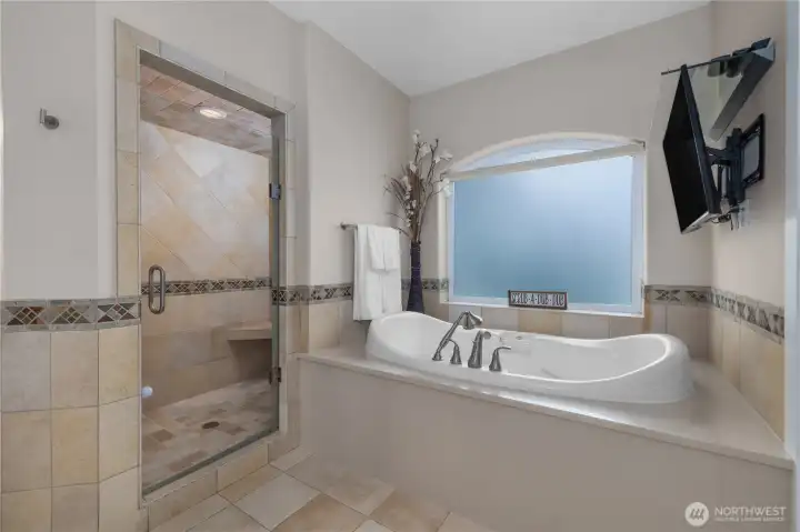 A soaking tub and tiled walk-in shower create a comfortable primary bath retreat.