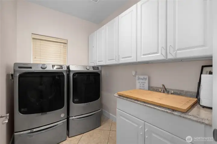 The laundry room includes storage cabinets, a utility sink, and practical counter space.