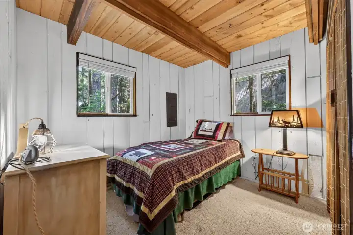 Main-level guest bedroom with wood ceilings, natural light, and closet storage. Main-level guest bedroom with wood ceilings, natural light, and closet storage.