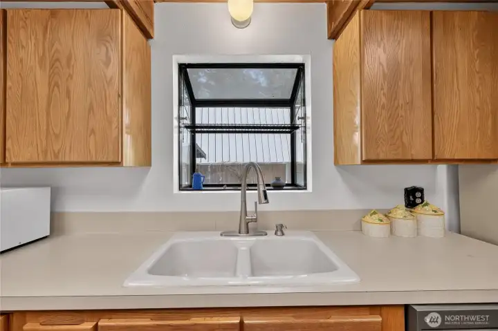 Kitchen workspace featuring a large window above the sink and additional cabinet storage. Kitchen workspace featuring a large window above the sink and additional cabinet storage.