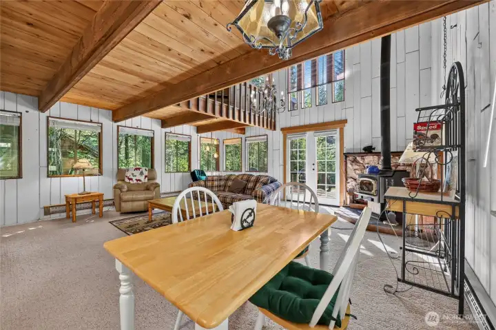 Great room featuring vaulted tongue-and-groove wood ceilings, exposed beams, and expansive windows. Great room featuring vaulted tongue-and-groove wood ceilings, exposed beams, and expansive windows.