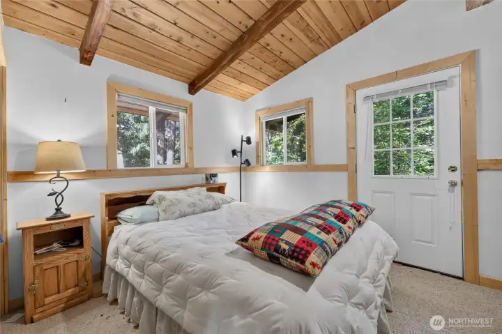 Primary bedroom featuring vaulted wood ceilings and private deck access. Primary bedroom featuring vaulted wood ceilings and private deck access.