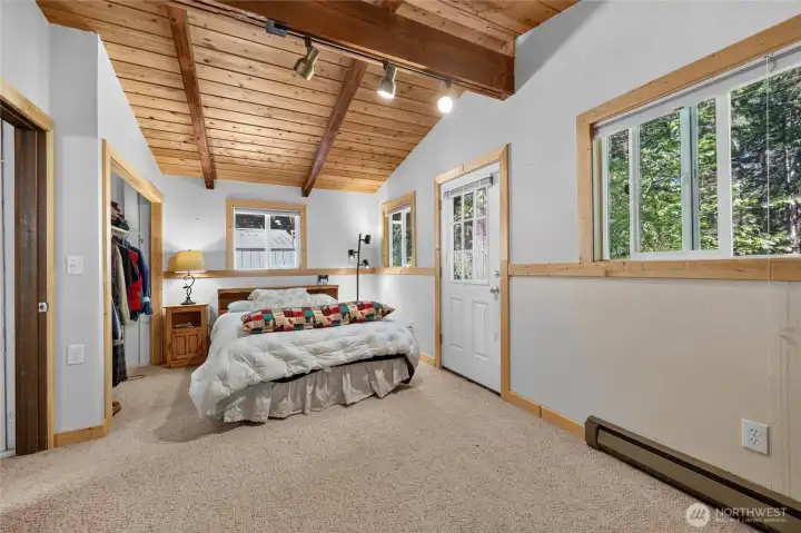 Spacious primary suite with multiple windows providing natural light and forest views. Spacious primary suite with multiple windows providing natural light and forest views.