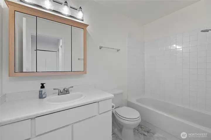 Main bathroom offers plenty of space and storage, brand new light fixture and tiled surround on shower/tub!