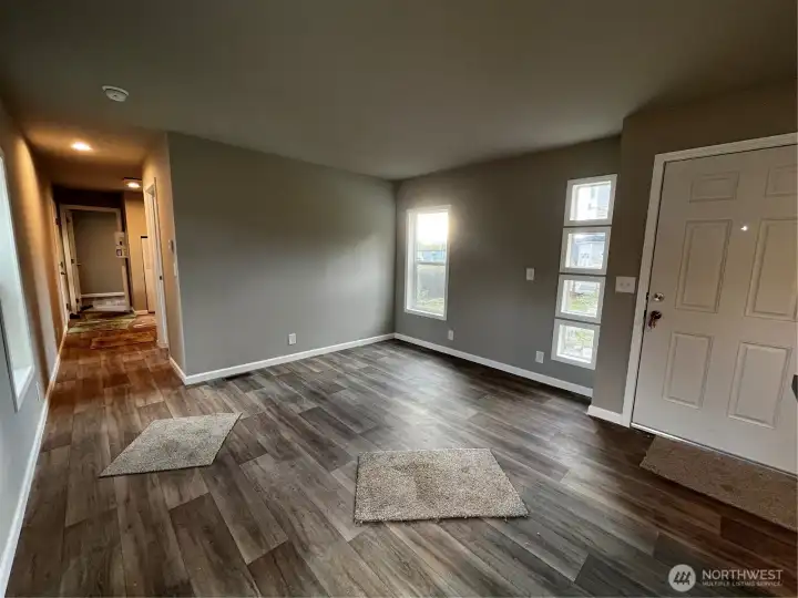 Main entrance leads into living room. Linoleum throughout home. Fun windows flank the front door.