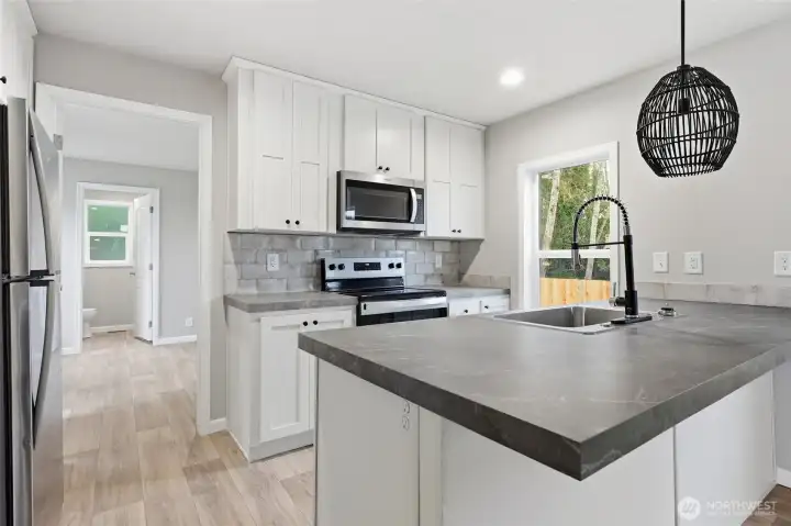 Kitchen with eat in bar and unique pendent light. All appliances come with home.