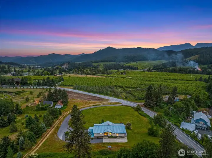 Elevated above the surrounding valley, this setting captures the essence of mountain living with sweeping views of rolling hillsides, open pastureland, and the orchards below.