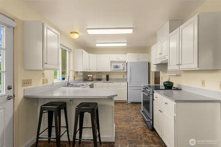 Spacious and efficient kitchen designed for everyday functionality, featuring abundant cabinetry, generous counter space, and an oversized breakfast bar ideal for casual dining or gathering.