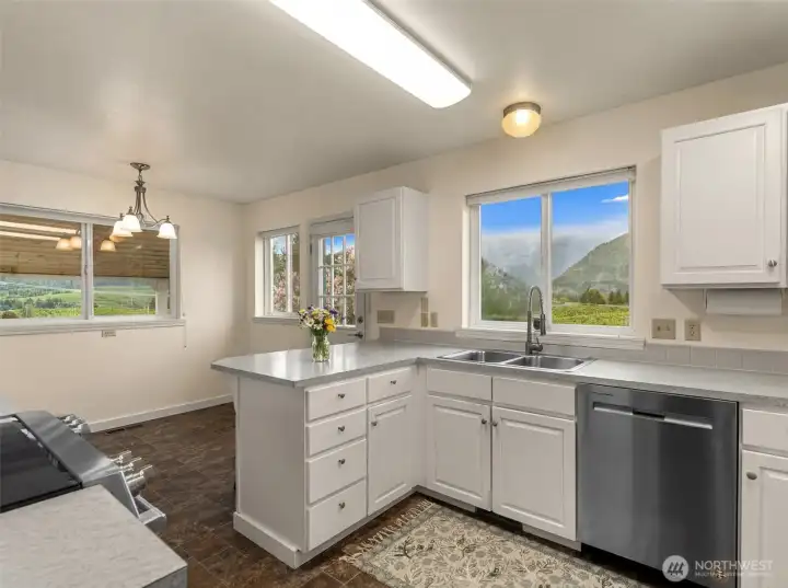 Crisp white cabinetry and expansive work surfaces create a bright, clean aesthetic, while the open layout offers seamless flow to the adjoining dining area and outdoor access.