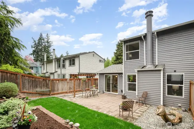 Serene backyard with large patio, grassy area and beautiful landscaping.