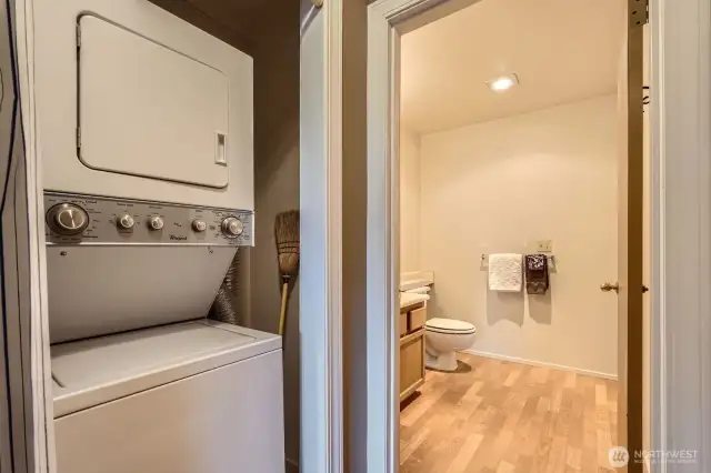A stacked washer and dryer in the hallway next to the half bath.