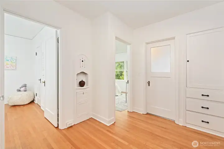 Wonderful vintage built-in linen and phone desk & seat create adorn a large central back hallway room separate from the living and dining areas
