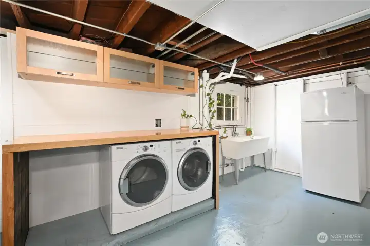 The largely clean but unfinished lower level, epoxy painted floors, a built in laundry counter made from reclaimed bowling alley material and features  tilt-up awing storage cabinets above.   A large laundry sink and second refrigerator comes with the home. Direct level access to the back yard with a large exterior awing above, is located to the left of the laundry.