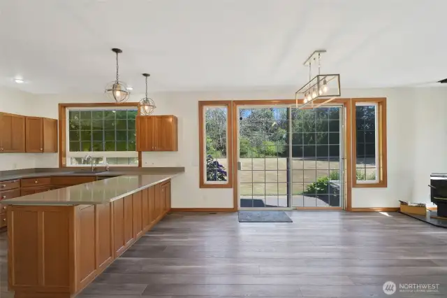 Another angle of the light-filled kitchen with a large central island, wood cabinetry, modern appliances, and open views into the dining and living area—ideal for entertaining.
