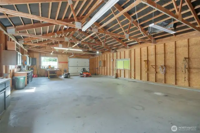 Massive detached shop with concrete floors, exposed beam ceiling, roll-up door, and built-in workbenches. Ideal for hobbies, equipment storage, or a home business setup.