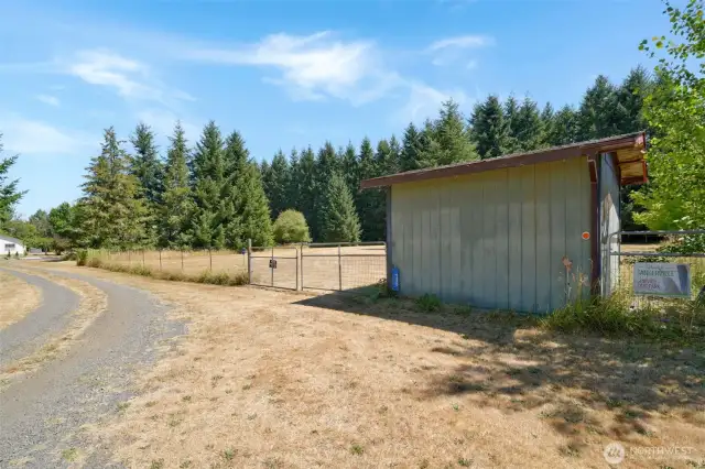 Gravel drive leads to a large fenced pasture with gated entry. A small outbuilding sits at the entrance, horse ready shed indicating current or prior use as an animal-friendly space.