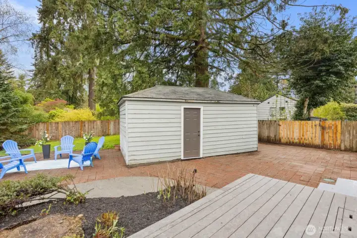 Large private backyard with deck, patio, open space, and private garage/storage.