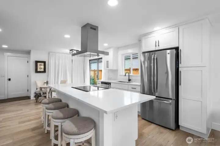 The island anchors the space, connecting the kitchen to three distinct living areas.