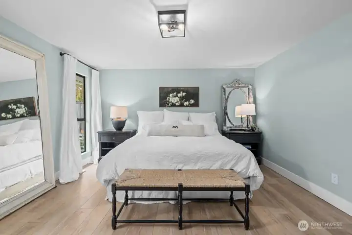 A generously sized retreat with room for a king bed, nightstands, a bench, and more — overlooking the garden beyond.
