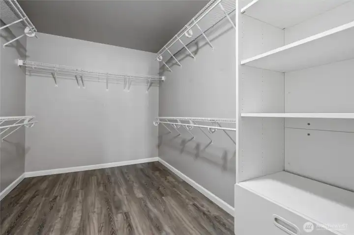 The capacious primary bedroom closet is fitted with shelves, rods and drawers.