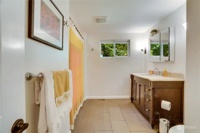 The full bath is set in the hall near all the bedrooms. A tile floor, vanity with plenty of drawers, mirrored medicine chest, window to the back yard, and a shower/tub complete the room.