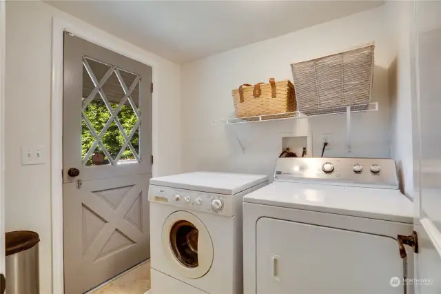 The laundry room stands just off the kitchen with a tile floor and a Dutch door that opens to a side porch with steps to the back yard.