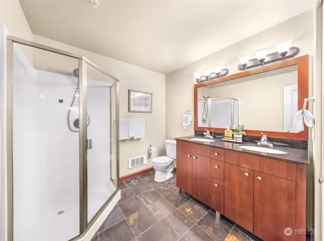 The primary bathroom features a walk-in shower, double vanity, slate floors and a closet.